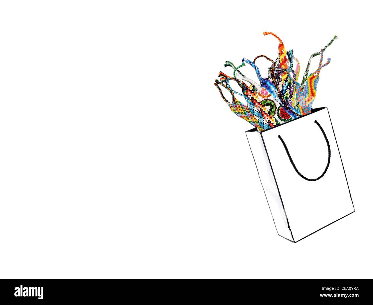 Weiße Papiertasche mit gewebten mehrfarbigen Freundschaft Armbänder auf weißem Hintergrund. Speicherplatz kopieren Stockfoto