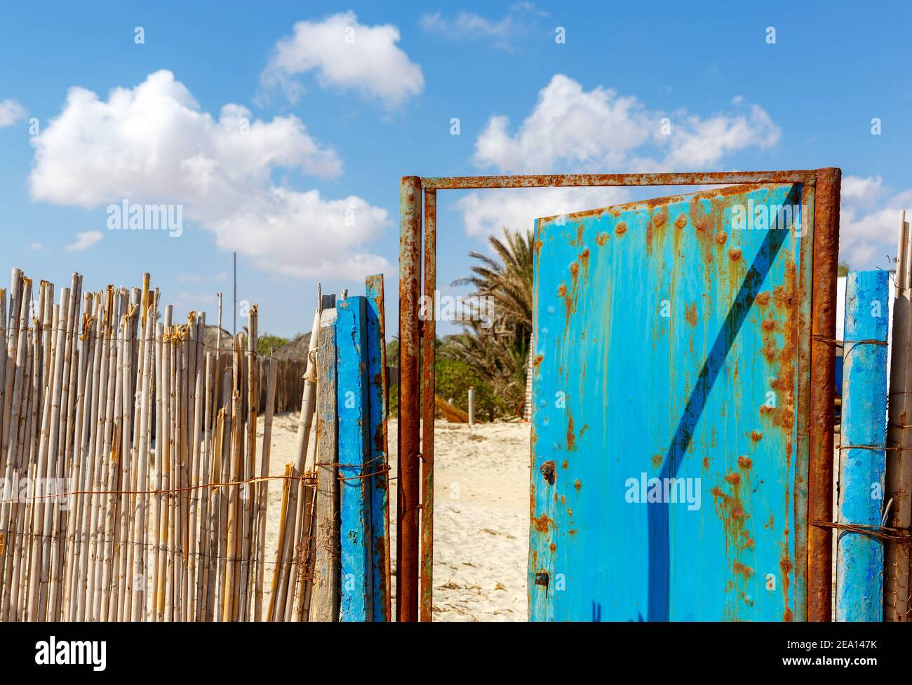 Bambuszaunung mit einer alten rostigen Metalltür Stockfoto