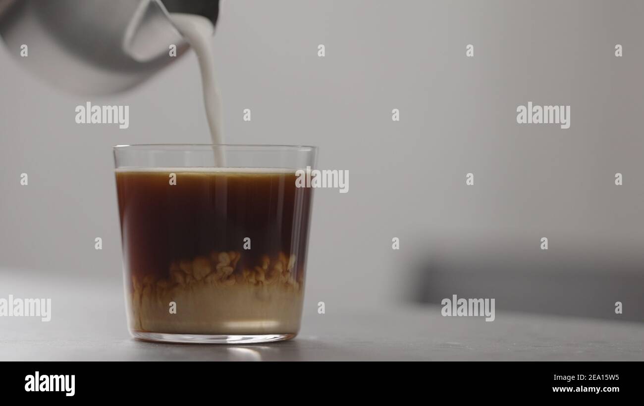 Gießen Sie Milch in Kaffee in Glas auf Beton Arbeitsplatte mit Kopierraum,  breites Foto Stockfotografie - Alamy
