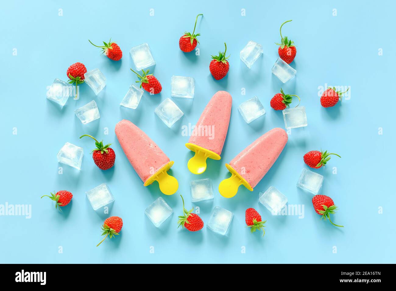 Hausgemachte Eiszapfen. Natürliches Eis in hellen Plastikformen, Erdbeeren und Eiswürfel auf blauem Hintergrund. Draufsicht Flat Lay. Stockfoto