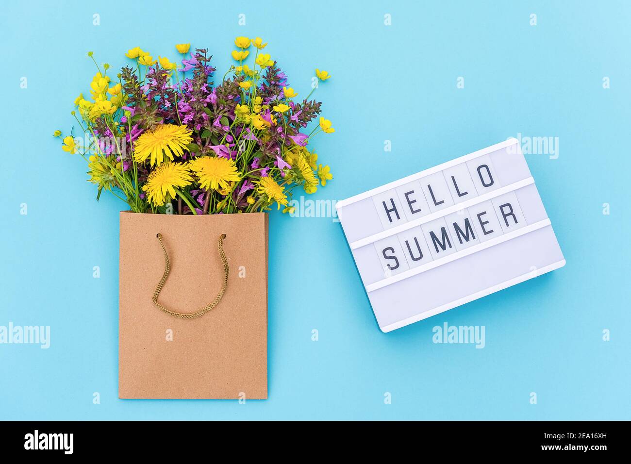 Text Hallo Sommer auf Leuchtkasten und hellen Strauß von Wildblumen in Handwerk Paket auf blauem Hintergrund. Konzept Sommerzeit. Draufsicht flache Lay-Vorlage Stockfoto