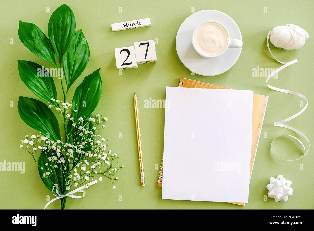 Holzwürfel Kalender März 27. Notizblock, Tasse Kaffee, Blumenstrauß auf grünem Hintergrund. Konzept hallo Frühjahr Creative Draufsicht Flat Lay Mock up. Stockfoto