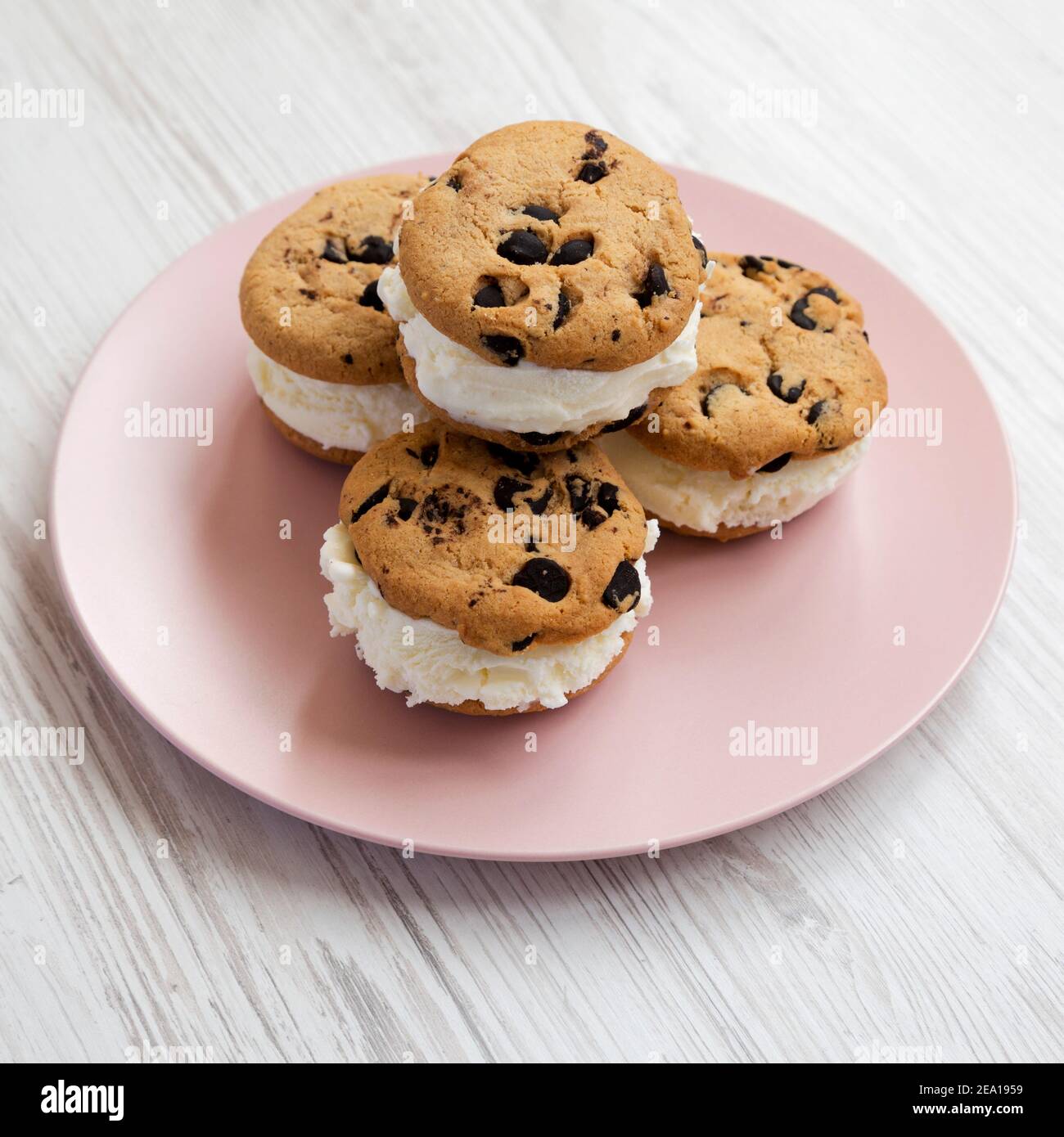 Hausgemachte Schokolade Chip Cookie Ice Cream Sandwich auf einem rosa Teller auf einem weißen Holztisch, Seitenansicht. Nahaufnahme. Stockfoto