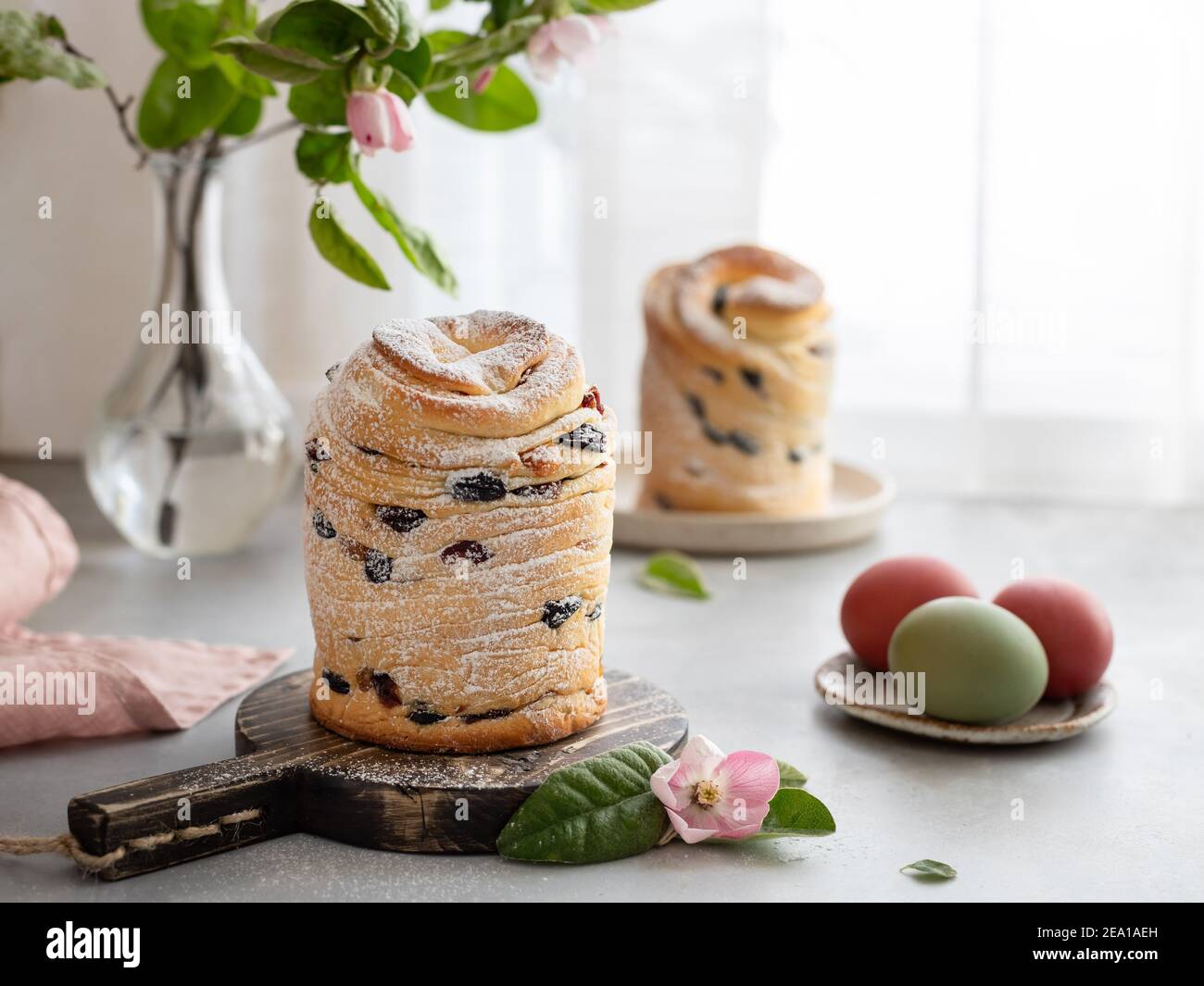 Osterkuchen Cruffin und bemalte Eier auf Fensterhintergrund Stockfoto