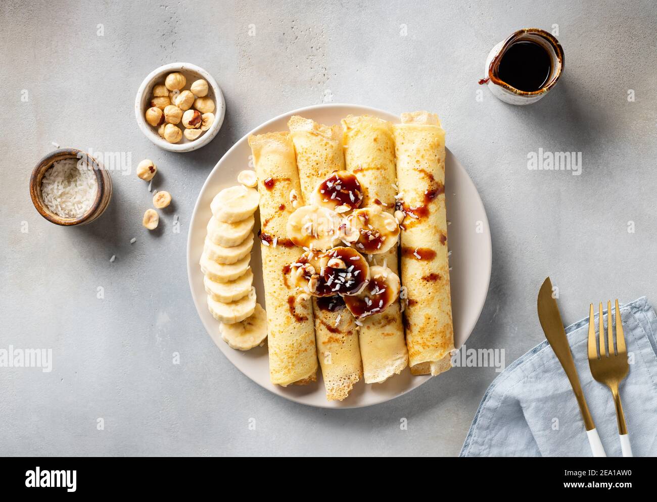 Gerollte Crepes mit Banane, Nüsse, Kokosnuss und Dattelsirup Stockfoto