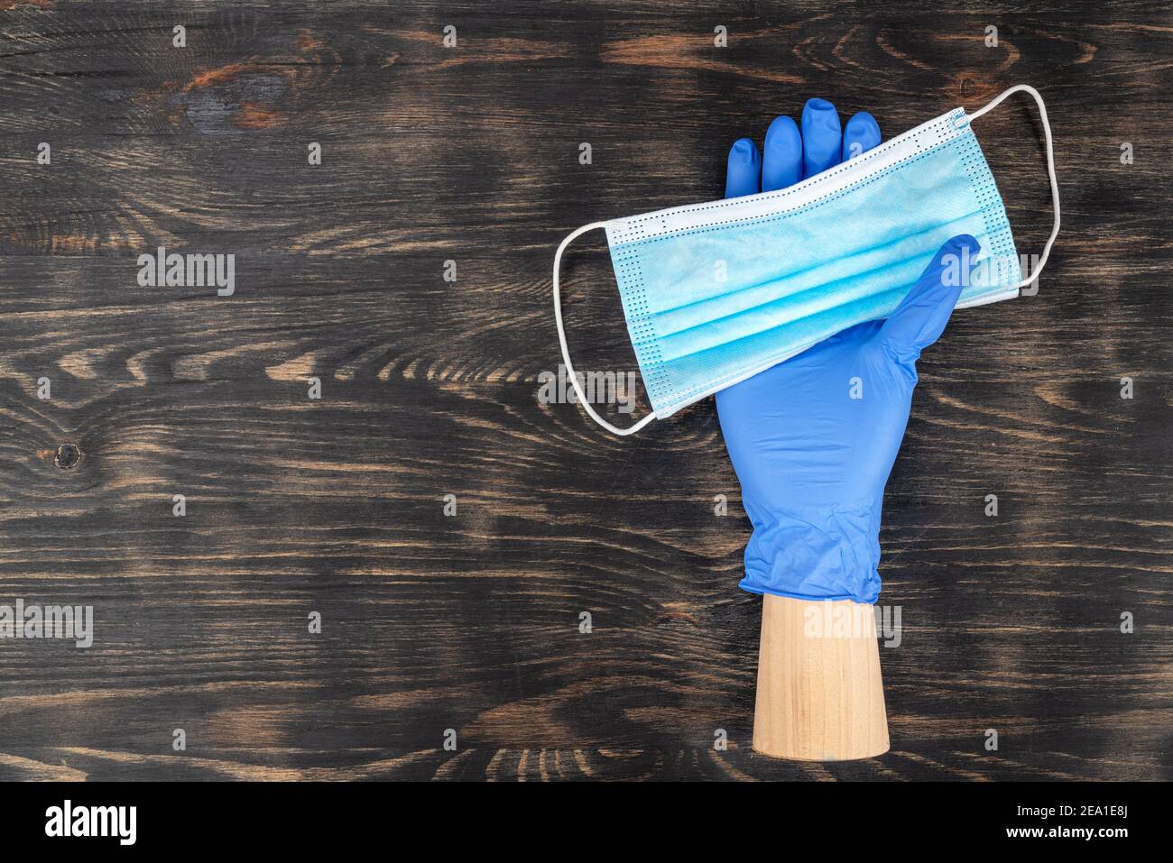 Schaufensterpuppe Hand trägt einen Einweghandschuh und hält eine medizinische Maske. Während der Quarantäne von covid19. Stockfoto
