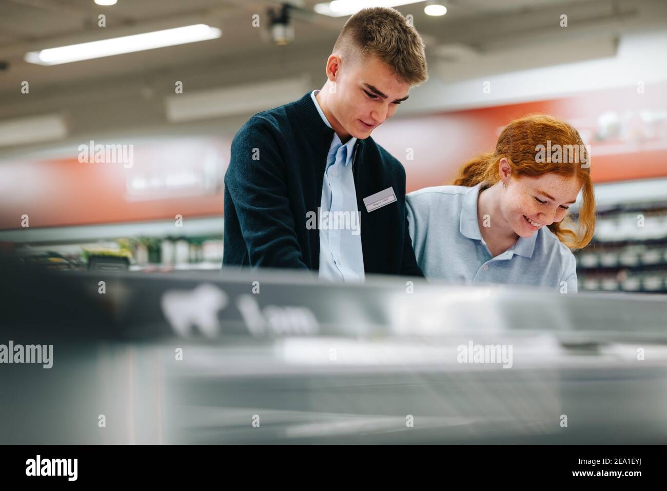 Junge Mitarbeiter im Lebensmittelgeschäft arbeiten zusammen. Zwei Supermarktassistenten arbeiten. Stockfoto