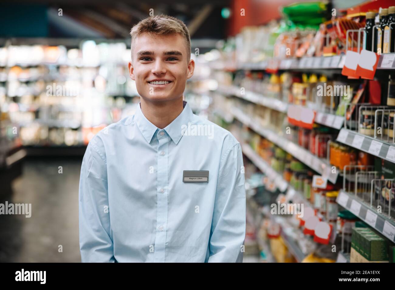 Porträt eines jungen Studenten, der im Lebensmittelgeschäft arbeitet. Mann im Urlaub Job in einem modernen Supermarkt. Stockfoto