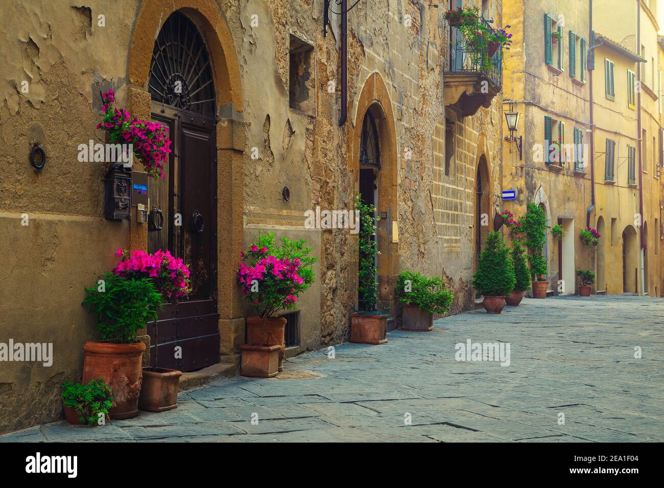 Tolle aussicht auf die toskanische Straße. Nette mittelalterliche Steinhäuser und gepflasterte Straße mit blumigen Eingängen, Pienza, Toskana, Italien, Europa Stockfoto