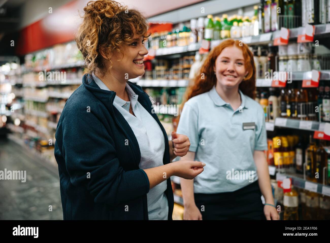 Trainer, der einer neuen Mitarbeiterin die Fähigkeiten im Kundenservice vermittelt. Supermarktmanager Ausbildung junge Arbeitnehmerin. Stockfoto
