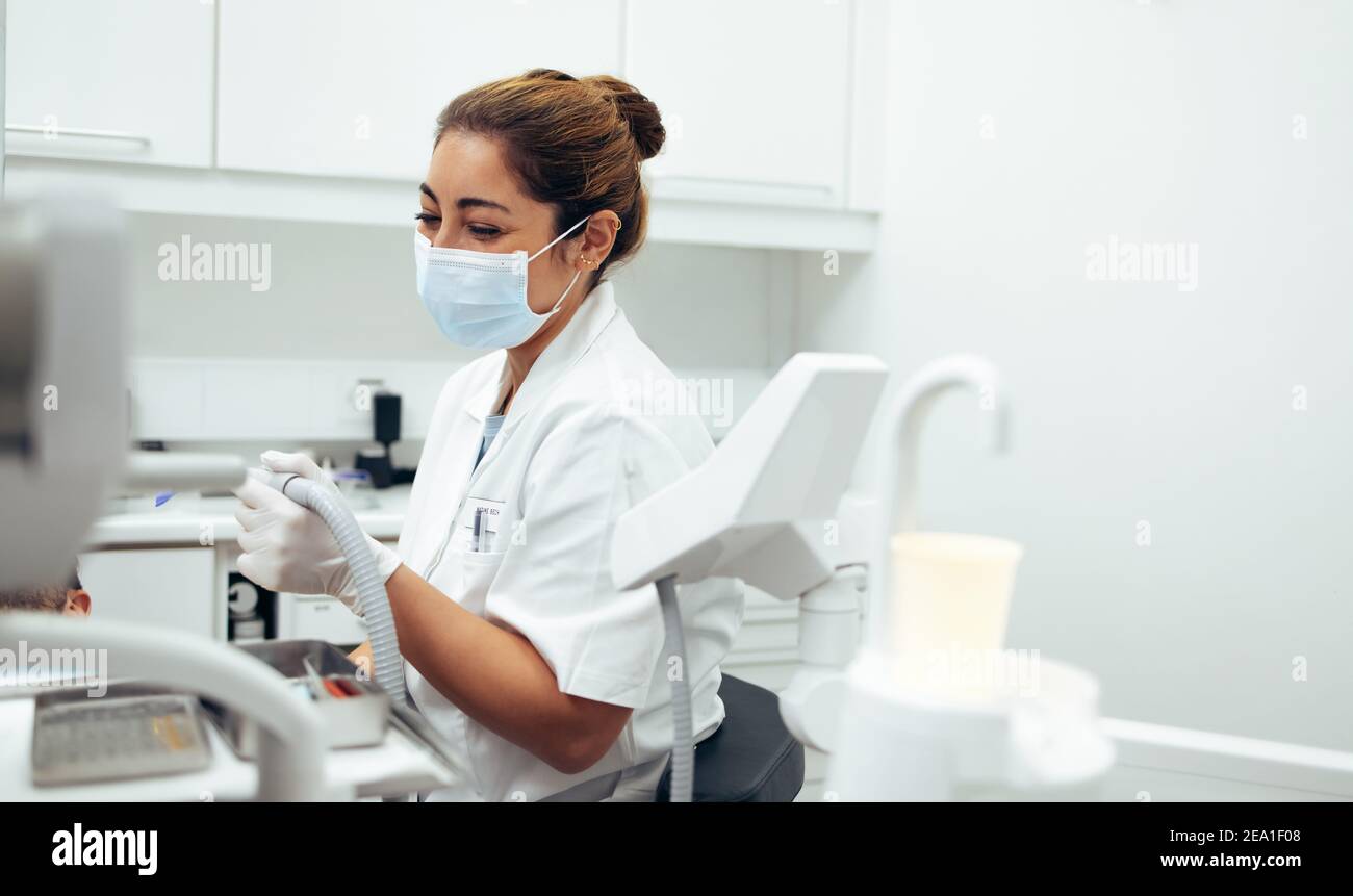 Zahnarzt, der eine zahnärztliche Behandlung in den Zähnen eines Patienten mit Werkzeugen. Weibliche Zahnärztin trägt Gesichtsmaske arbeiten in ihrer Klinik. Stockfoto