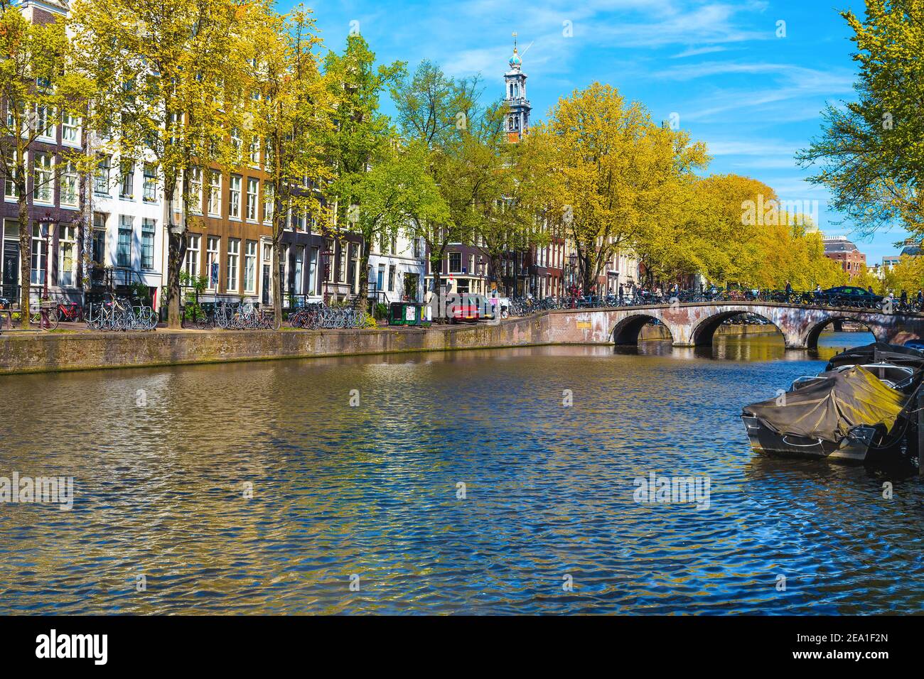 Gemütliche Straßen- und Ufergebäude am Ufer des Wasserkanals. Frühling Stadtbild mit traditionellen Gebäuden und verankerten Booten in Amsterdam, Nethe Stockfoto