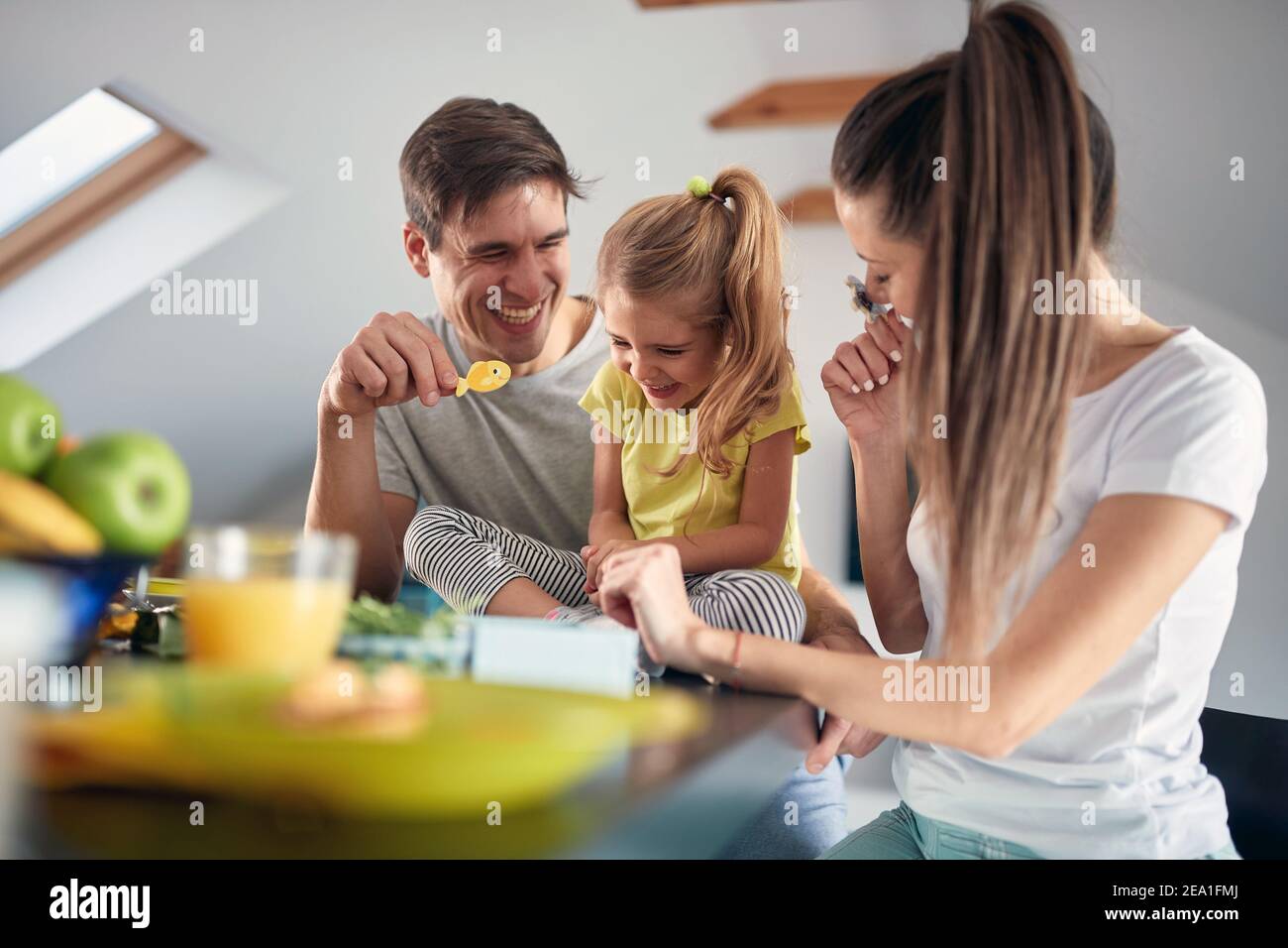 Eine junge glückliche Familie, die sich nach einem Frühstück in einer fröhlichen Atmosphäre zu Hause zusammen gut Vergnügen kann. Familie, Frühstück, zusammen, Zuhause Stockfoto