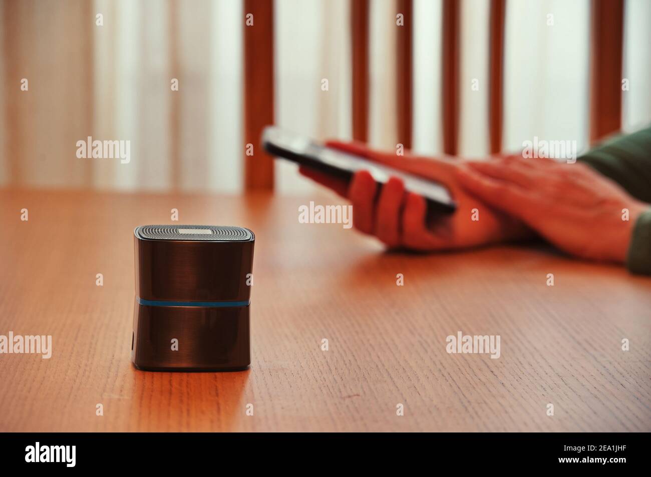 Bluetooth-Lautsprecher vor den Händen der Frau, die das Mobiltelefon hält Stockfoto