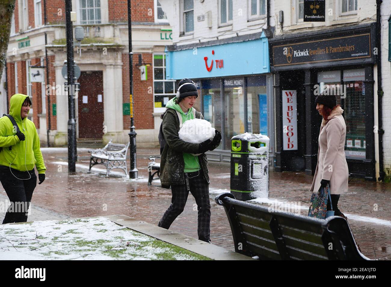 Ashford, Kent, Großbritannien. Februar 2021, 07. UK Wetter: Sturm Darcy trifft die Stadt Ashford in Kent. Ein junger Mann trägt einen Schneeball entlang der Hauptstraße. Foto-Kredit: Paul Lawrenson/Alamy Live Nachrichten Stockfoto