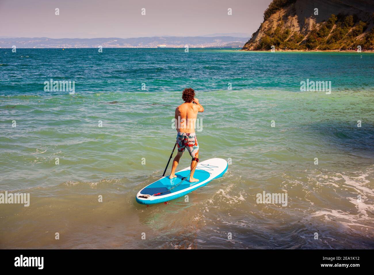 Stand Up Paddle Boarding. Fröhlicher Mann trainiert an einem sonnigen Morgen SUP-Board in der adria. Strunjan, Slowenisch Stockfoto