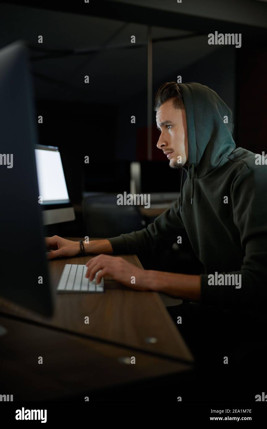 Junge Internet-Hacker im Hood sitzen an Monitoren Stockfoto