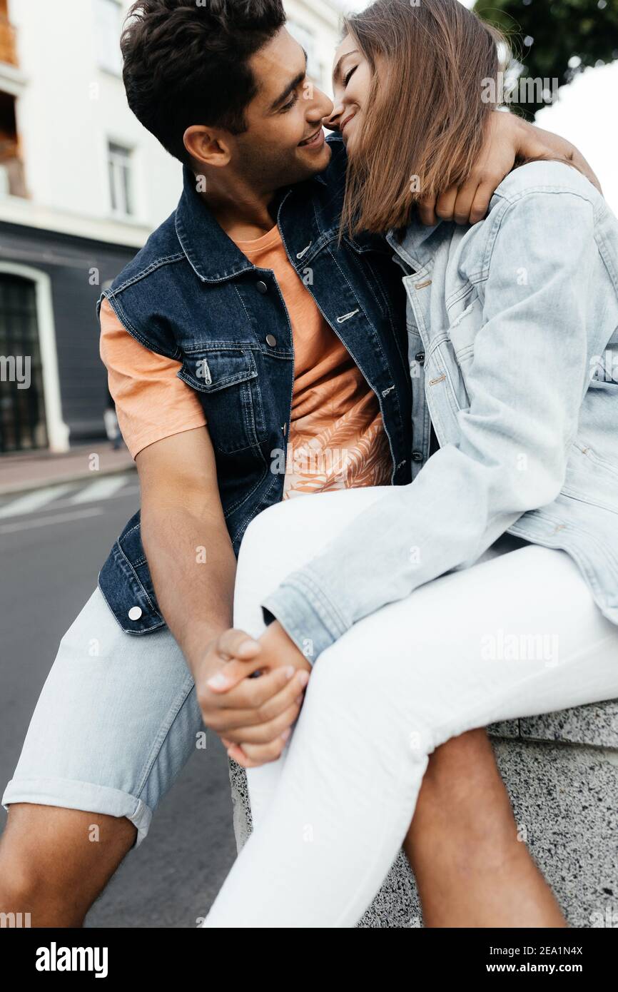 Liebhaber küssen auf der Straße. Mann und Frau in der Jeansjacke, die sich küssen wird. Verliebte Paare in der Stadt. Urbane Liebesgeschichte Stockfoto