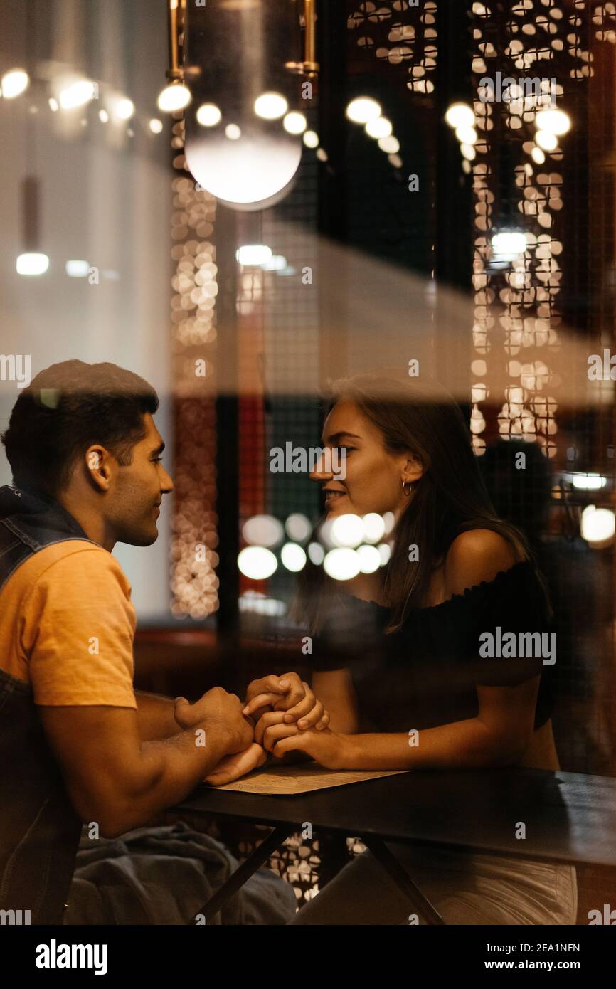 Verliebte Paare sitzen im Café und halten sich die Hände. Sprechende Liebhaber. Mann und Frau Hintergrund Stockfoto