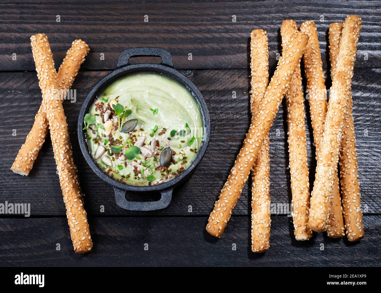Avocado Dip (Hummus) mit Knabbereien auf braunem Holzhintergrund, Text Freiraum Stockfoto
