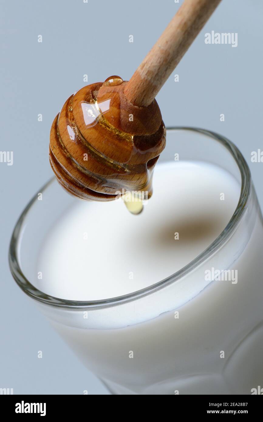 Honigmilch, Glas Milch mit Honig, Honiglöffel Stockfoto