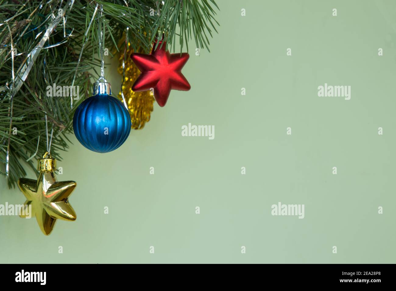 Weihnachtsdekoration. Natürliche Kiefernzweige auf grünem Hintergrund mit blauer Kugel und gelben roten Sternen und Neujahrsspielzeug. Speicherplatz kopieren. Stockfoto