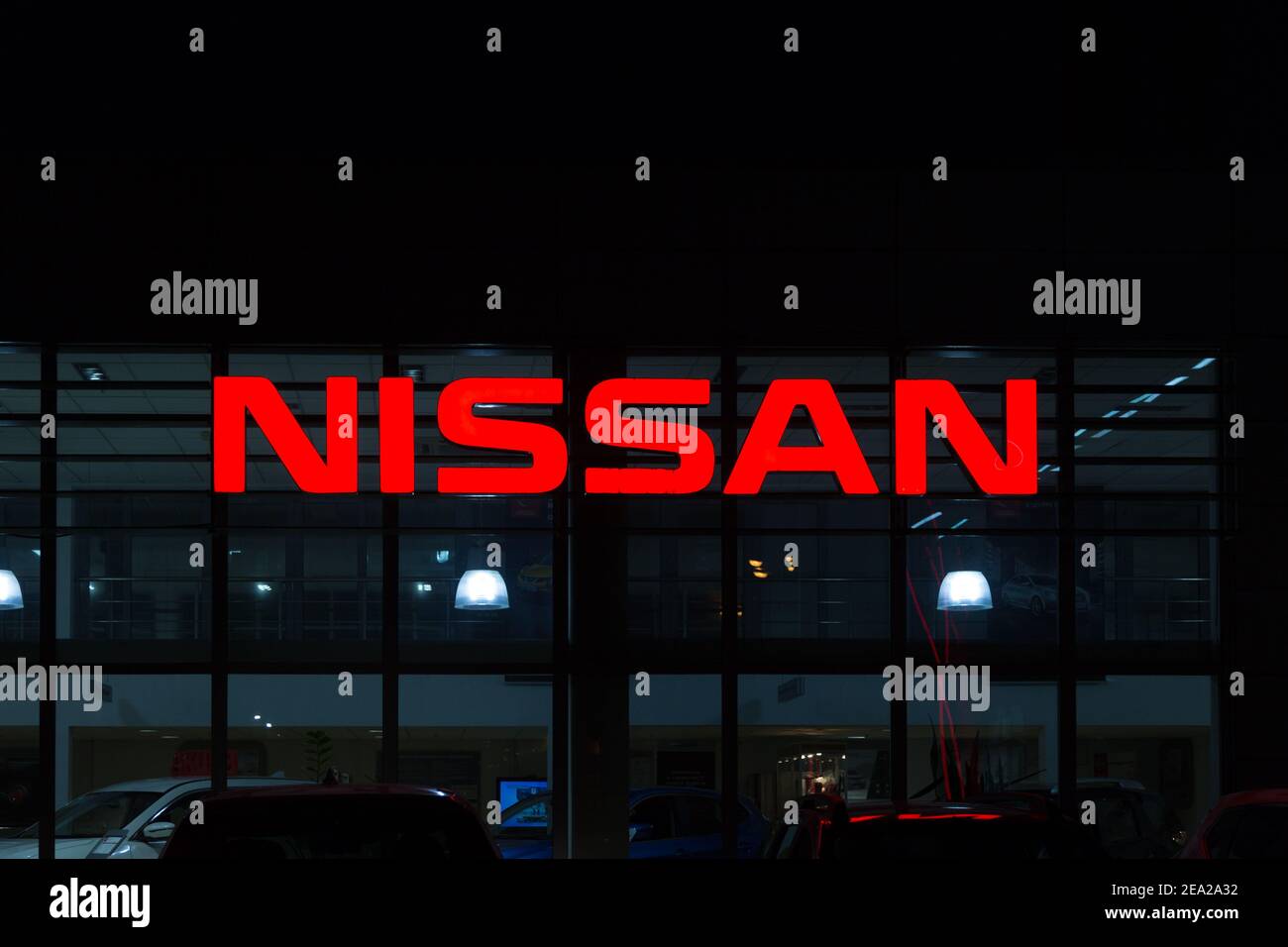 MOSKAU, RUSSLAND - NOVEMBER 24 2019: Neon-rotes Schild Nissan Night auf der Autoworld Auto Krylatskoye. In den dunklen Fenstern sind sichtbare Silhouetten von Autos Stockfoto
