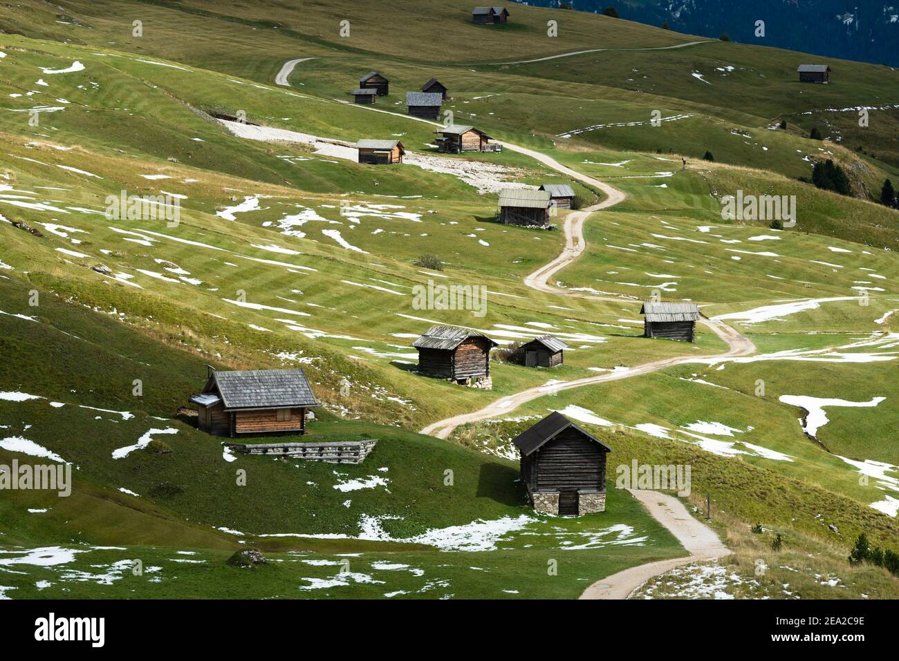 Auf den Wiesen der Petzer Alp unter dem Peitlerkofel im Herbst, Dolomiten, Südtirol, Italien liegen Holzhütten und Schnee Stockfoto