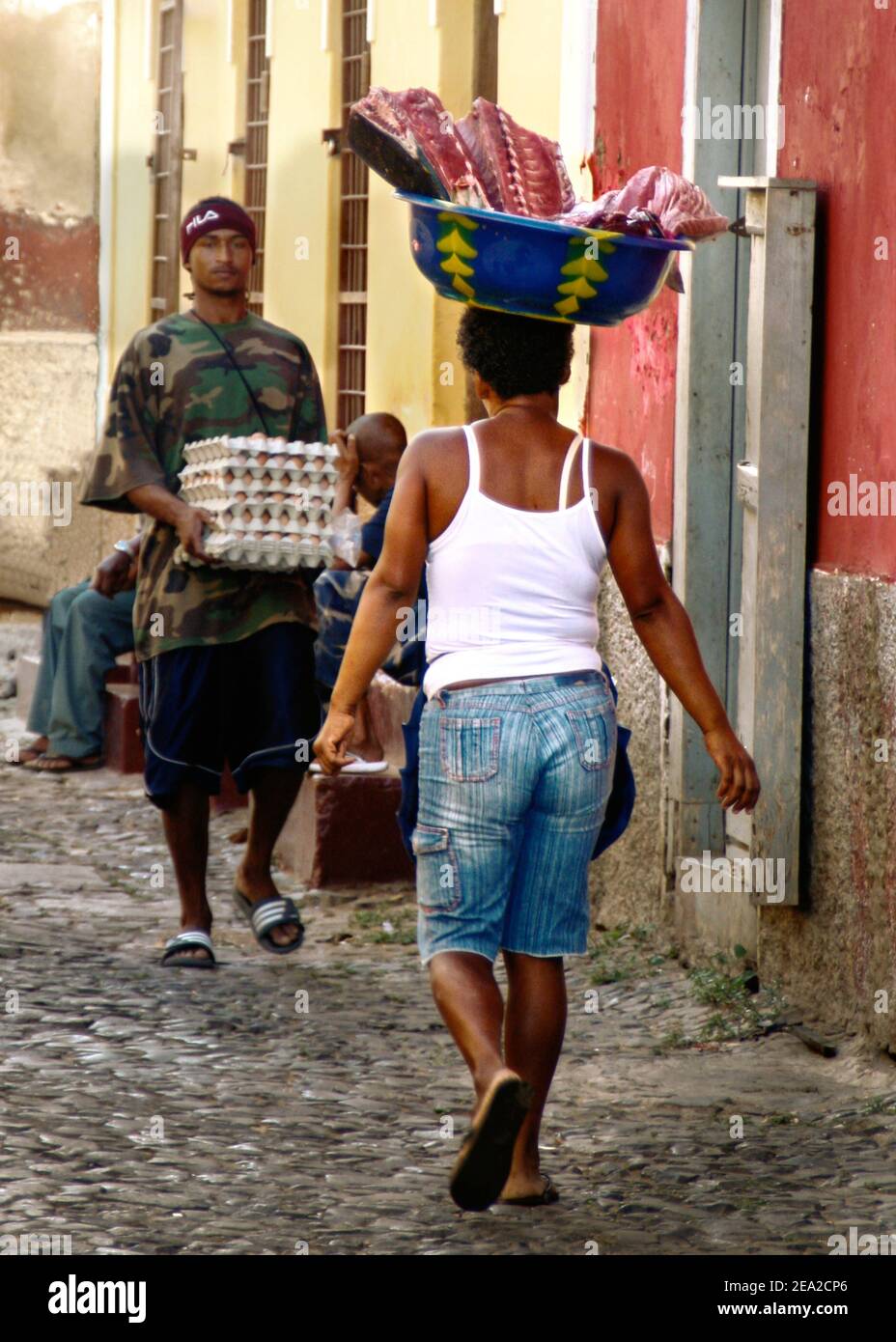 Straßenszene in Porto Grande, Sao Vincente, Kapverdische Inseln. Frauen tragen Fischlieferung auf ihrem Kopf. Farbenfrohe, gepflasterte Straßen. Stockfoto