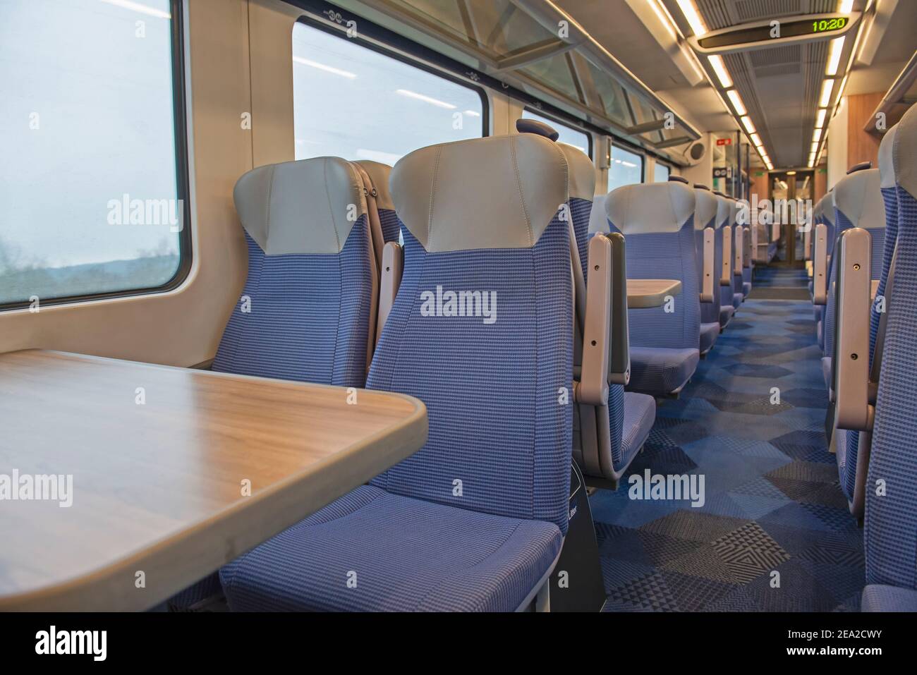 Blick auf das Innere in einem menschenleeren Pendlerzug Wagen Mit Sitzreihen und Tischen Stockfoto