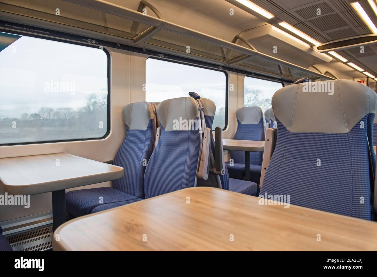 Blick auf das Innere in einem menschenleeren Pendlerzug Wagen Mit Sitzreihen und Tischen Stockfoto