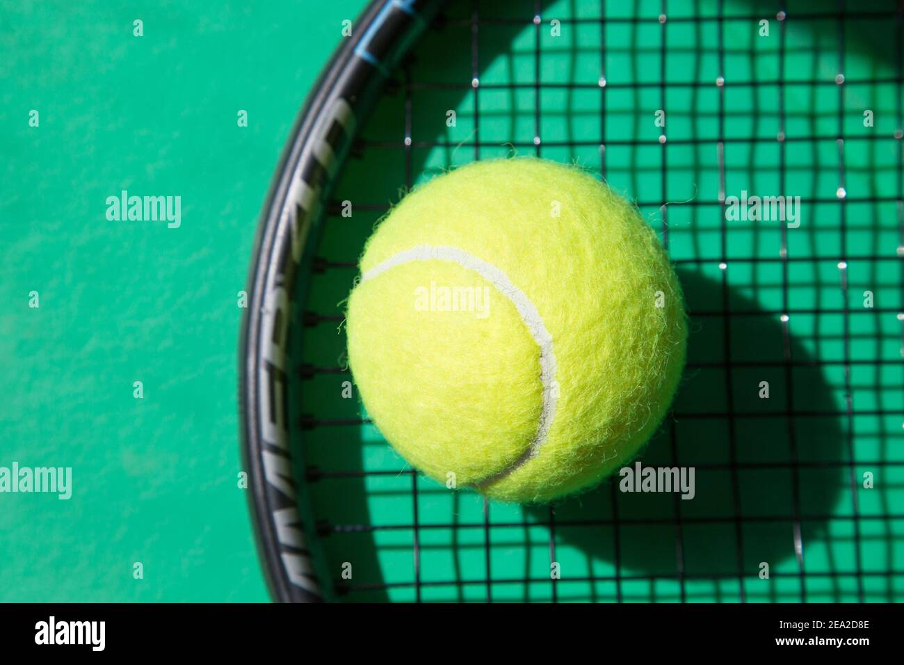 Nahaufnahme Tennisball auf Schläger und grünem Hintergrund. Konzept im Tennis. Stockfoto