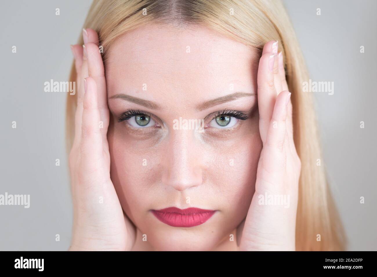 Müde weiße Frau hält ihren Kopf vor Problemen mit ihren Händen. Nahaufnahme Stockfoto