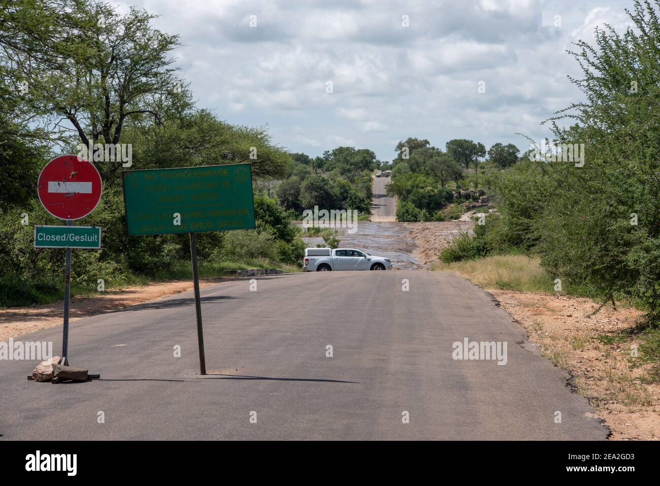 Eine Straße im Krüger Nationalpark wegen gesperrt Wasser fließt über die Brücke Stockfoto