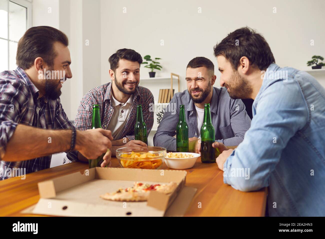 Vier fröhliche Männer Freunde, die zu Hause Party Treffen mit Bier Und Pizza Stockfoto