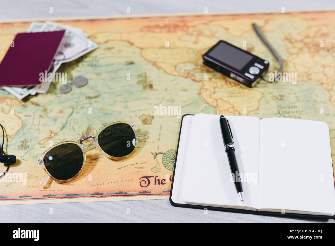 Reisevorbereitung Zubehör auf Weltkarte. Kamera, Pässe, Wechselstube, Sonnenbrille und Notizbuch zum Notizen machen. Reisevorbereitung Konzept Stockfoto