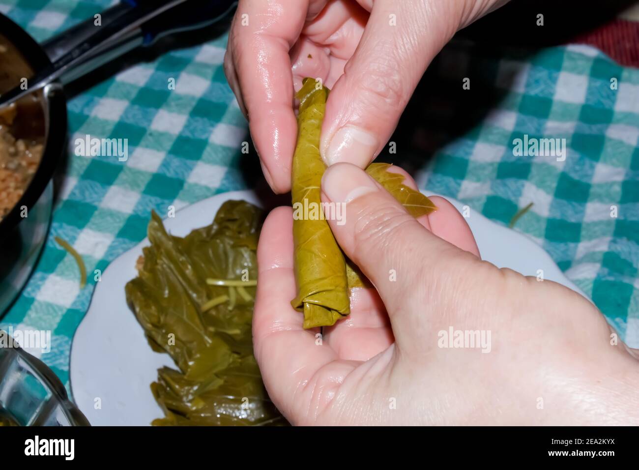 Frau wickelt Traubenblätter für Türkisch Sarma oder Dolma (Yaprak Sarma). Traditionelle türkische Küche. Hausmannskost-Konzept. Stockfoto