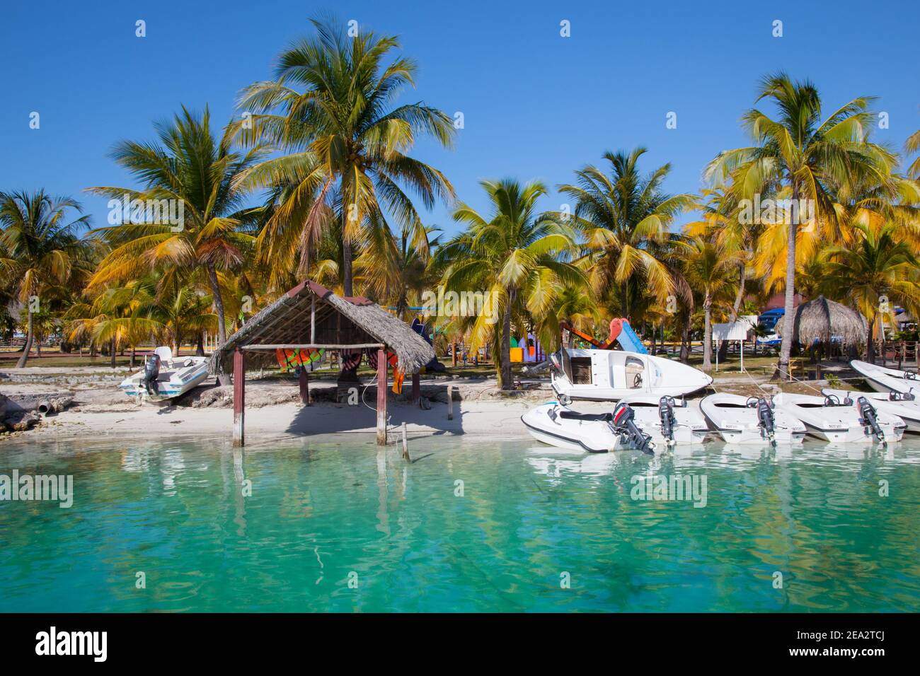 CAYO LARGO, KUBA:die Boote auf dem Hintergrund von smaragdfarbenem Wasser und Palmen sind bei Sonnenuntergang. Konzept Tourismus ist in Kuba Stockfoto