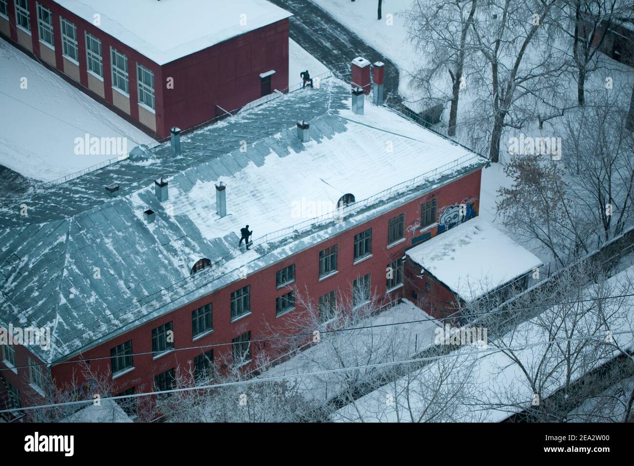 MOSKAU, RUSSLAND: Arbeiter reinigen das Dach von Schnee. Blaue Tonung. Russisches Frostkonzept Stockfoto
