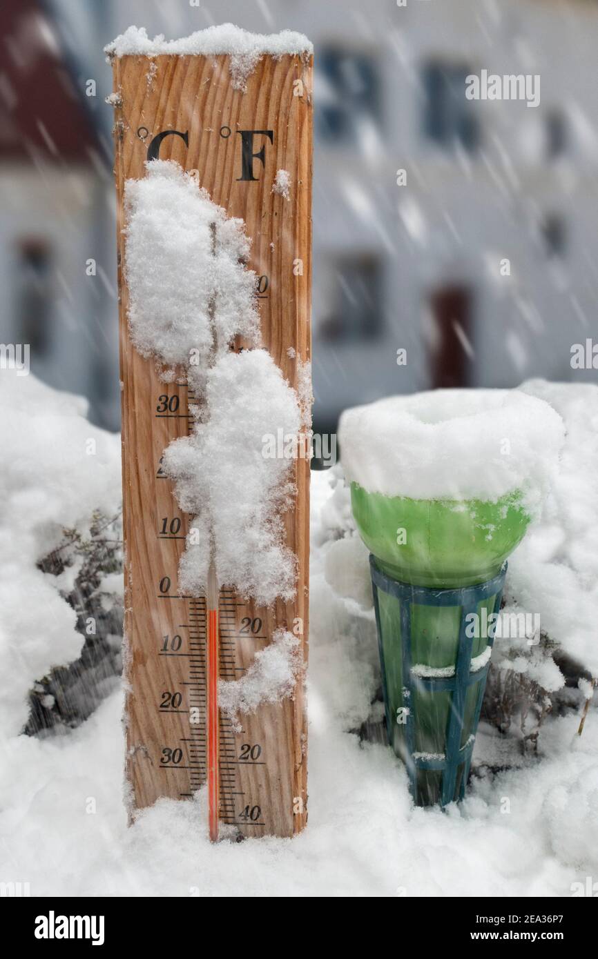 Regenmesser/Pluviometer für den Garten und Thermometer für den Außenbereich, die auf das Einfrieren hinweisen Temperatur von -2 Grad C 28 im Freien Schnee bei Schneefall im Winter Stockfoto