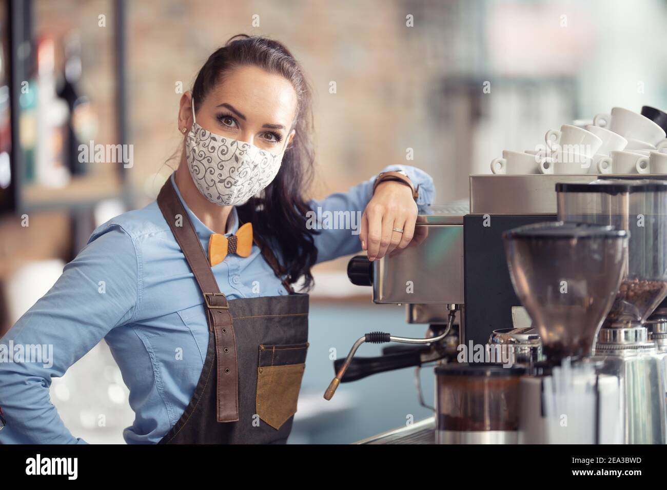 Frau trägt Schutzmaske bei der Arbeit, arbeitet als Kellnerin in einem Kaffeehaus. Stockfoto