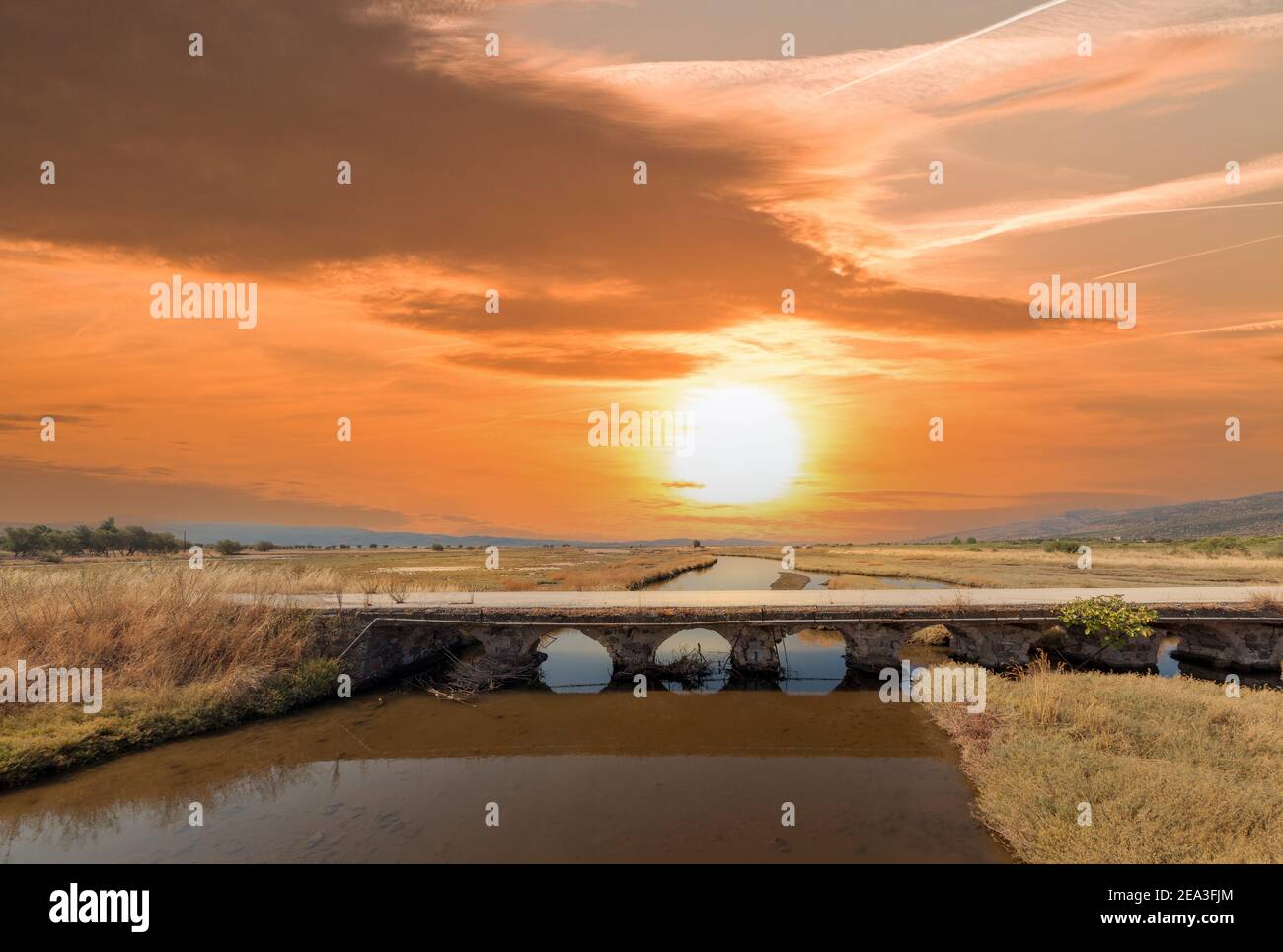 Alte Steinbrücke über einen Fluss bei Sonnenuntergang. Die Brücke heißt "neun Bögen" (Ennia Kamares) und befindet sich in der Nähe von Kalloni Stadt, in Lesvos, Griechenland Stockfoto