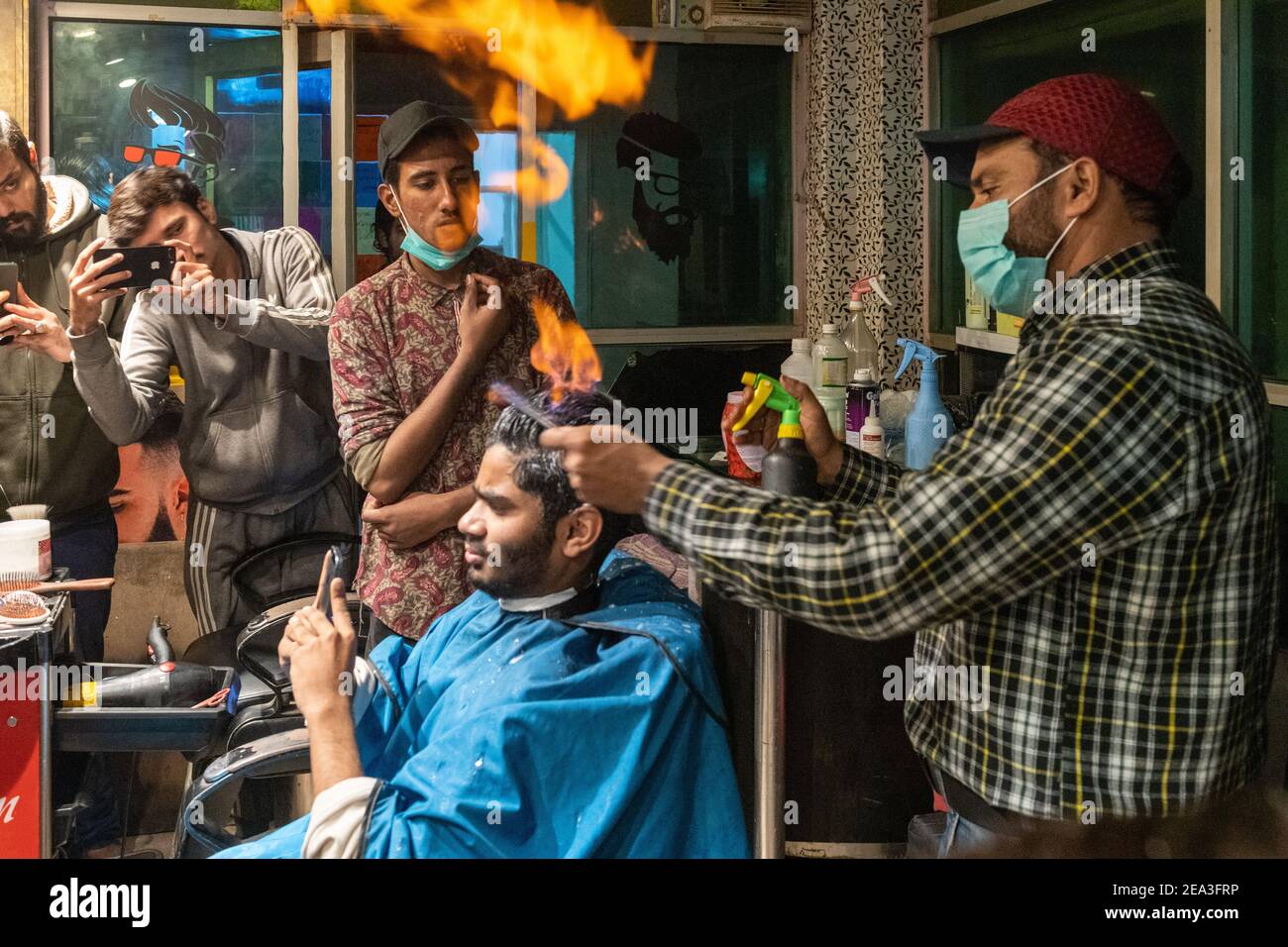 In Lahore hat ein Friseur eine einzigartige Technik entwickelt, um Herrenhaare zu schneiden: Er setzt das Haar in Flammen Stockfoto