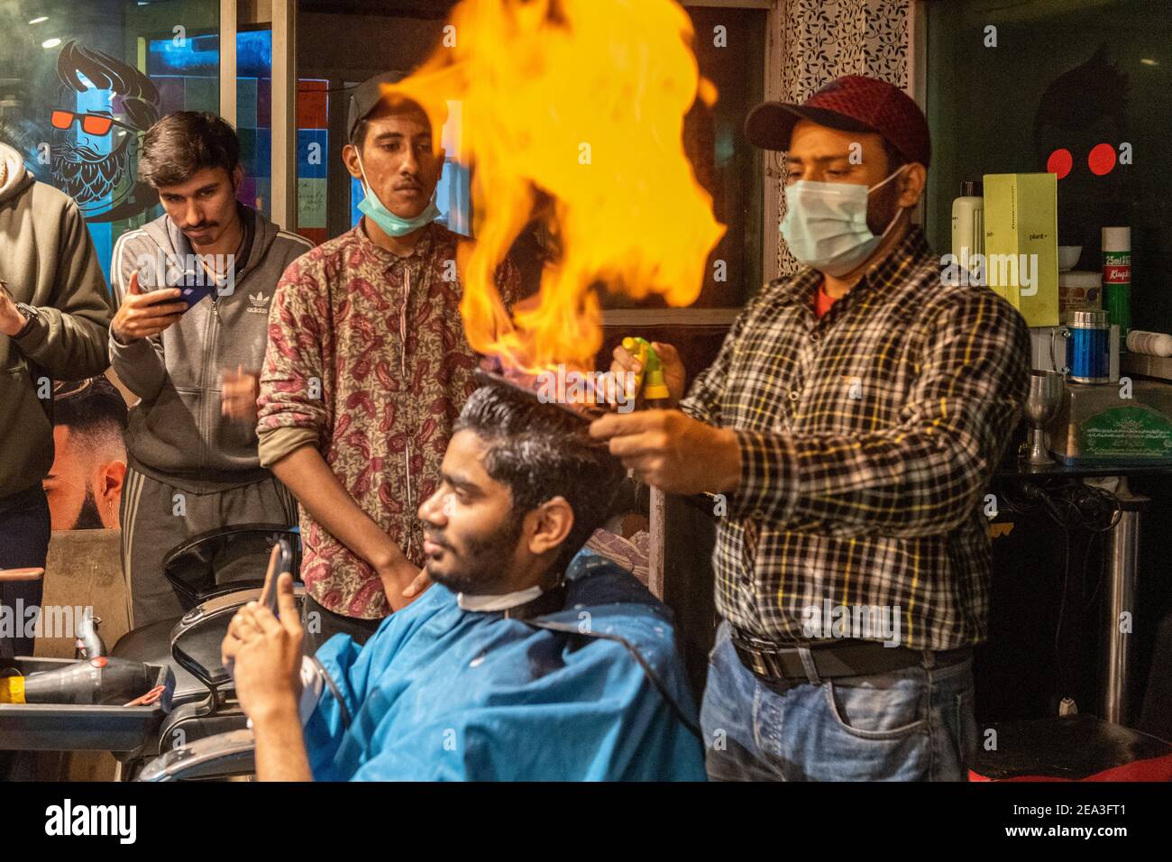 In Lahore hat ein Friseur eine einzigartige Technik entwickelt, um Herrenhaare zu schneiden: Er setzt das Haar in Flammen Stockfoto