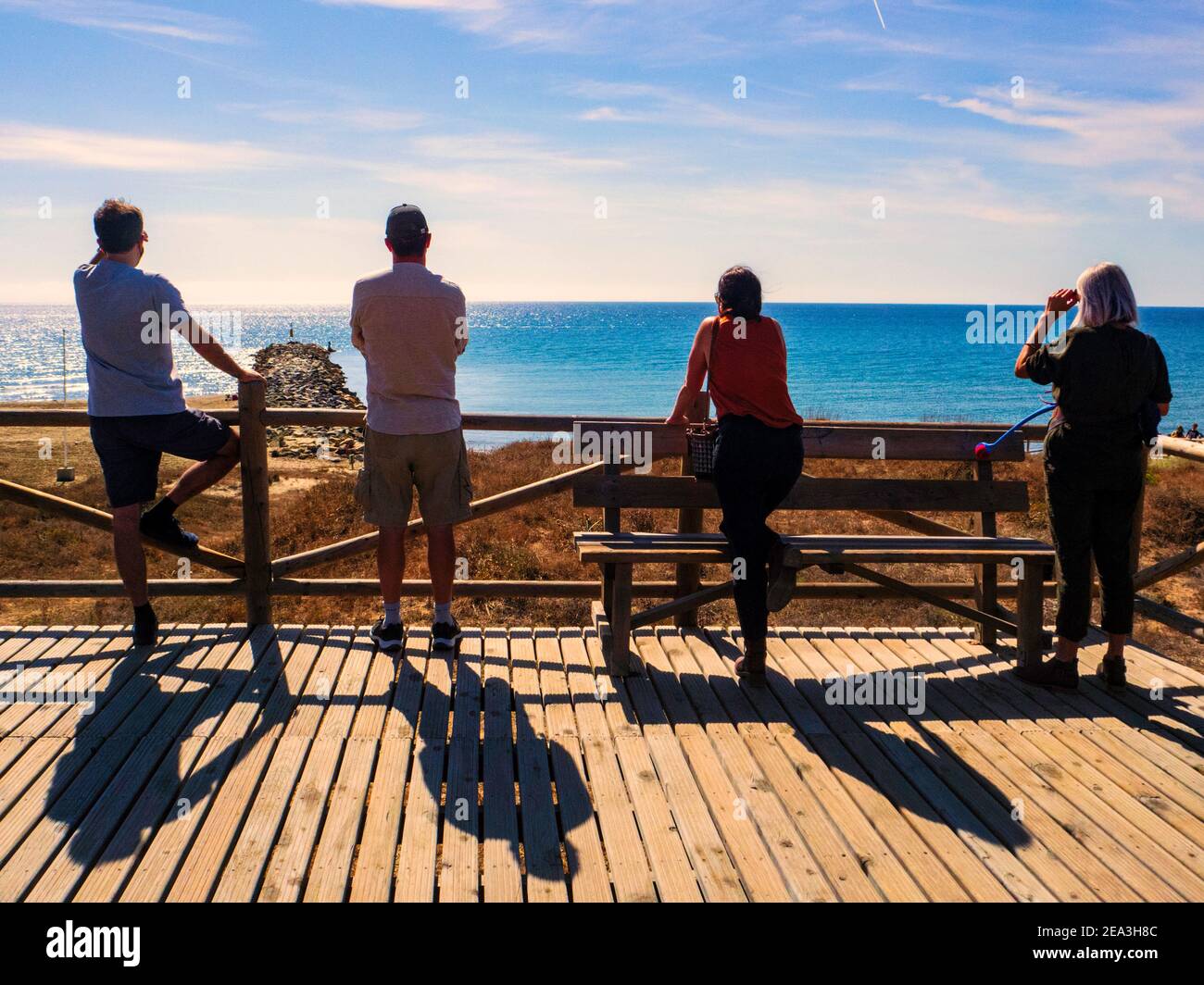 Marbella, Malaga, Spanien. Oktober 2020. Vier Touristen mit dem Rücken und Blick auf das Meer auf einer hölzernen Aussichtsplattform an der Küste von Marbella Stockfoto