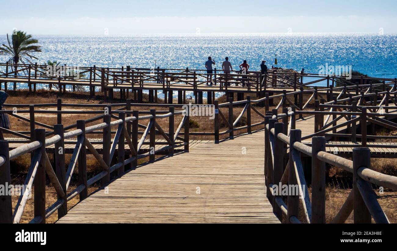 Marbella, Malaga, Spanien. Oktober 2020. Vier Touristen mit dem Rücken und Blick auf das Meer auf einer hölzernen Aussichtsplattform an der Küste von Marbella Stockfoto