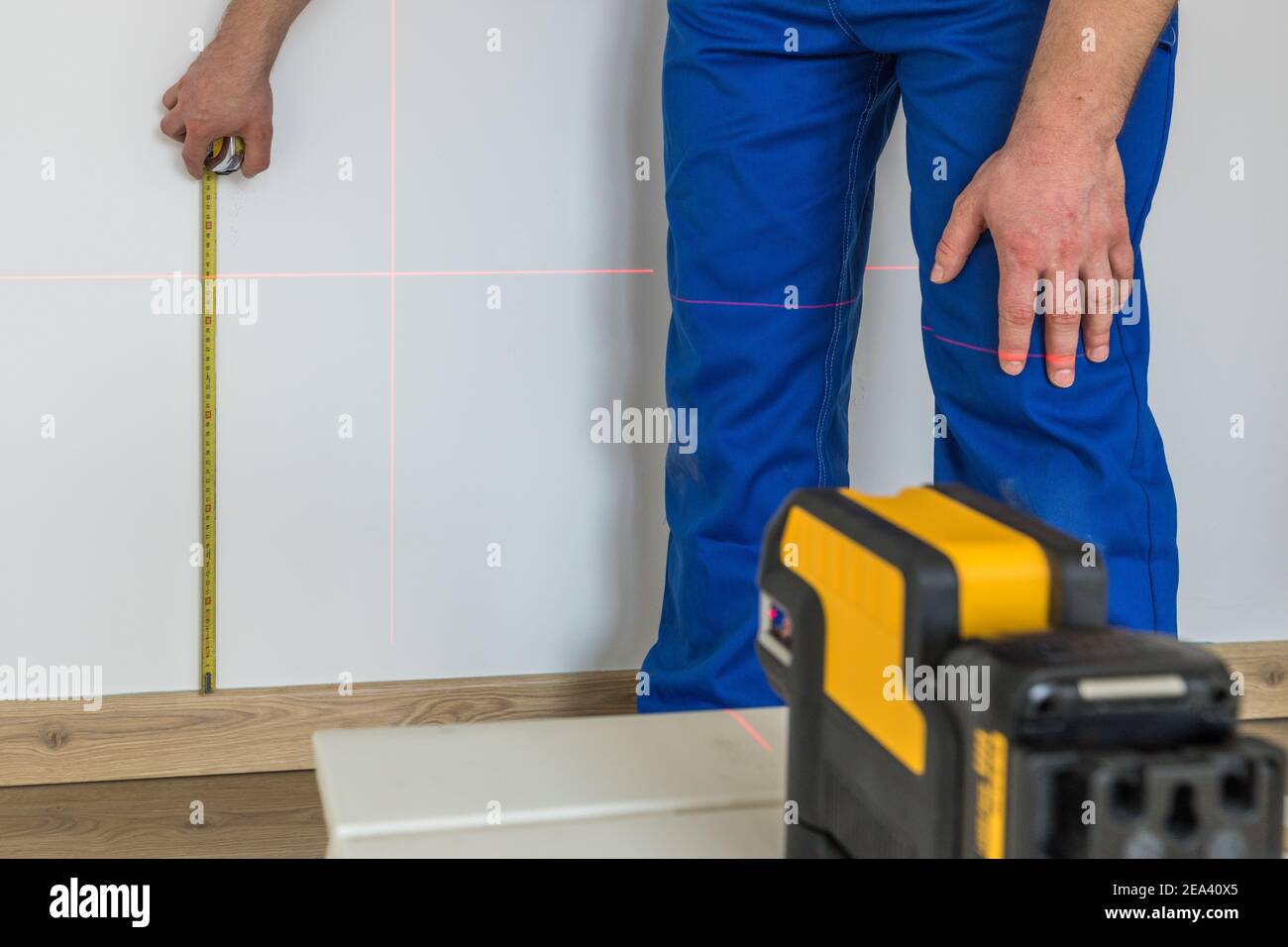 Ein Spezialist nimmt Messungen an der Wand mit einer Messung vor Stick und ein elektronischer Laser zur Anzeige von Füllständen und Senklot Stockfoto