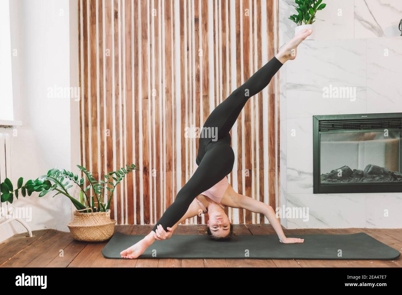 Junge fit flexible Frau trägt Sportkleidung tun Dehnübungen Aufenthalt auf dem Kopf im Wohnzimmer. Training im Innenbereich. Training zu Hause Stockfoto