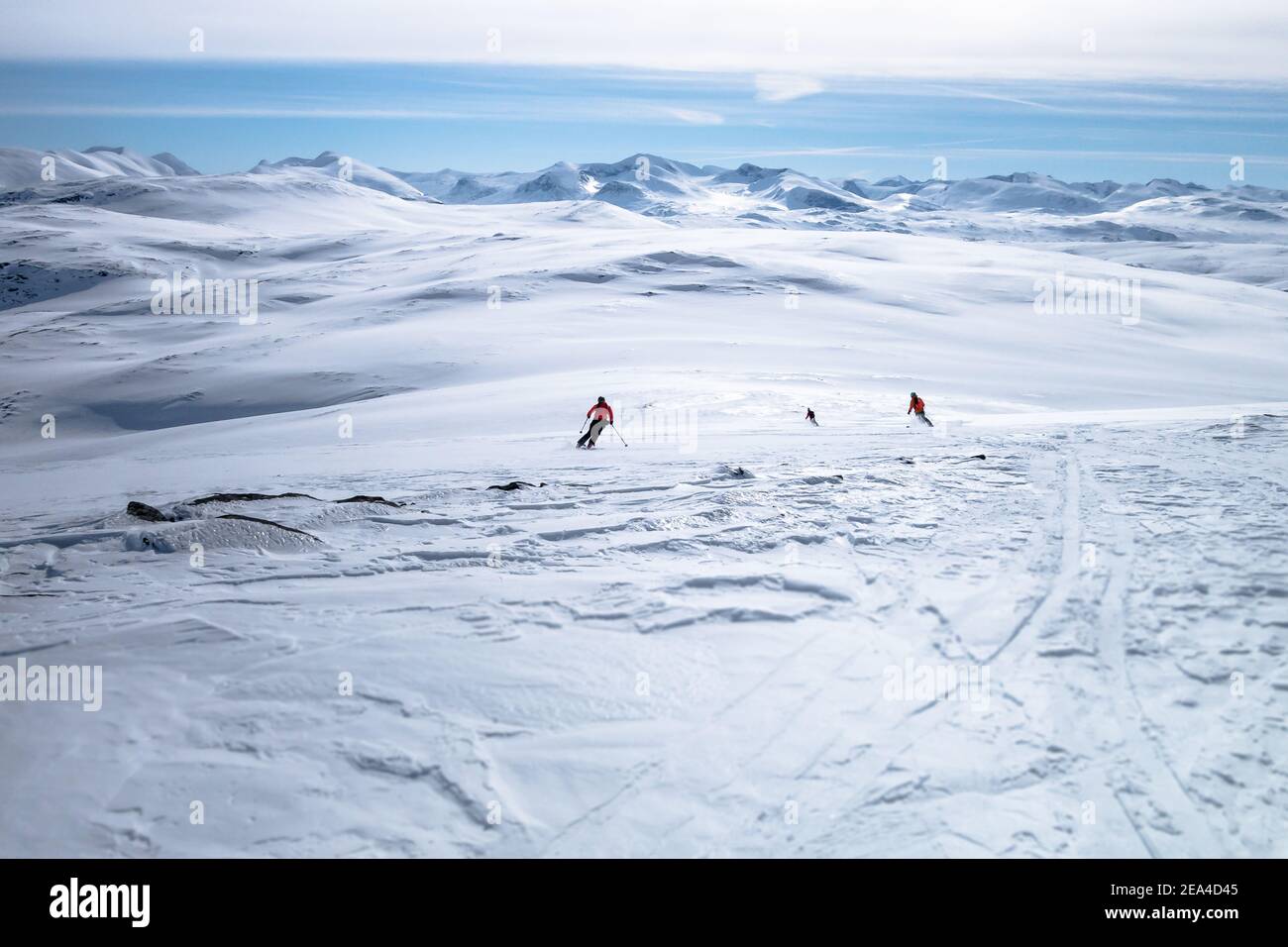 Drei Skifahrer, die am Horizont in Richtung der Bergketten fahren Auf dem Pulverschneeplatz in Lappland, Schweden Stockfoto