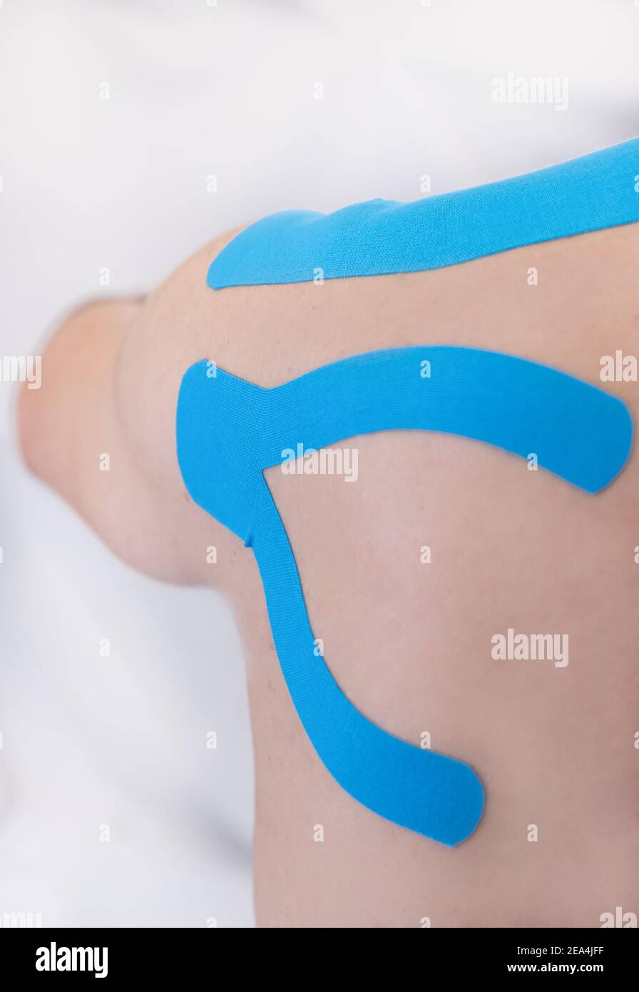 Eine vertikale Aufnahme einer Schulter, die von kinesiologischen Bändern bedeckt ist Auf weißem Hintergrund Stockfoto